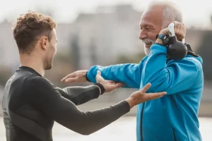 Entrenador corrigiendo la postura de un hombre mayor que sostiene una pesa rusa