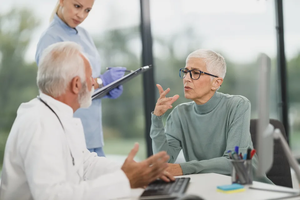 Médico explicando un informe a una mujer mayor sentada en la consulta