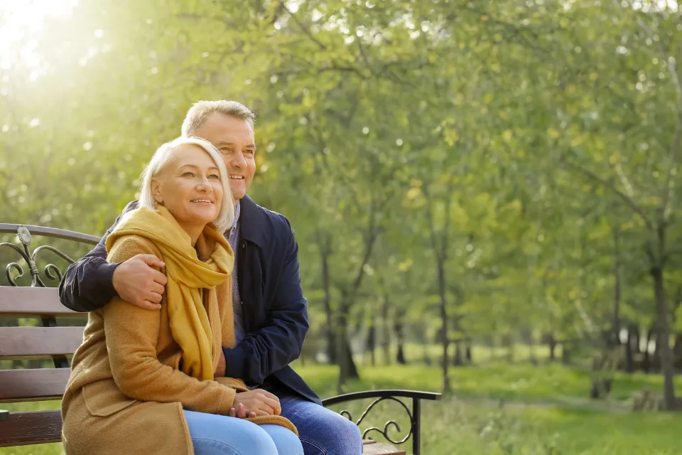 Pareja de mediana edad sentada en un banco de un parque en otoño