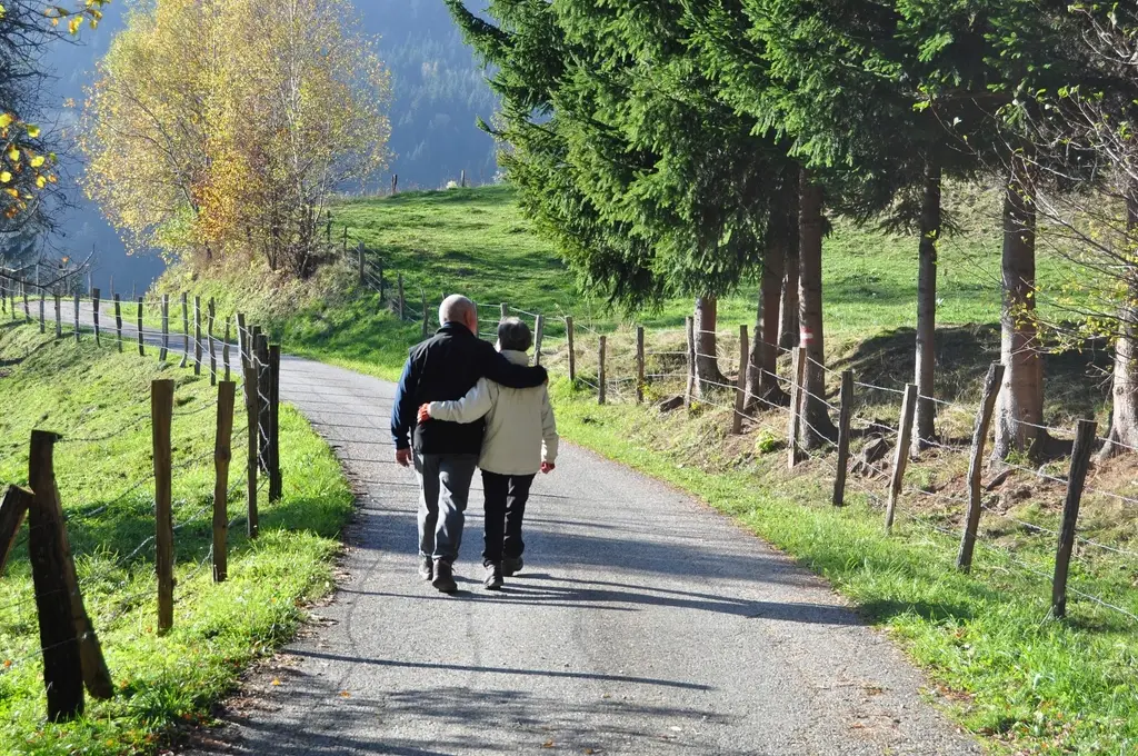 Pareja de unos sesenta años caminando por un sendero arbolado en otoño