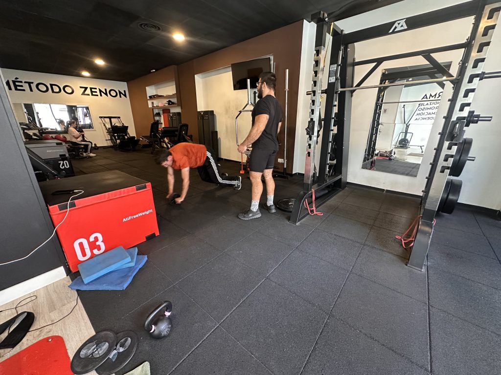 Entrenador de Método Zenon supervisando a un cliente en la sala de fuerza